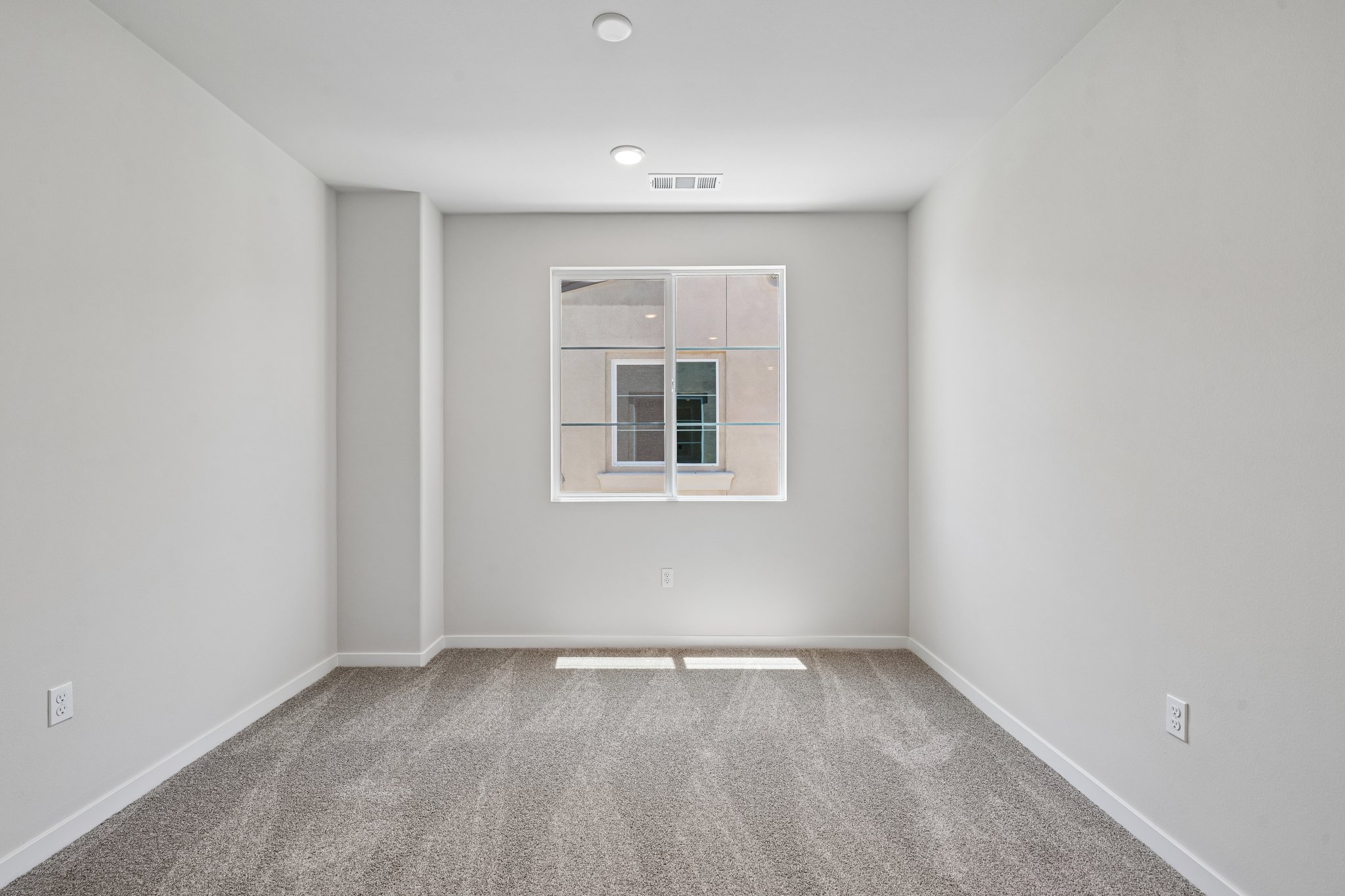 A room with a window and a carpet.