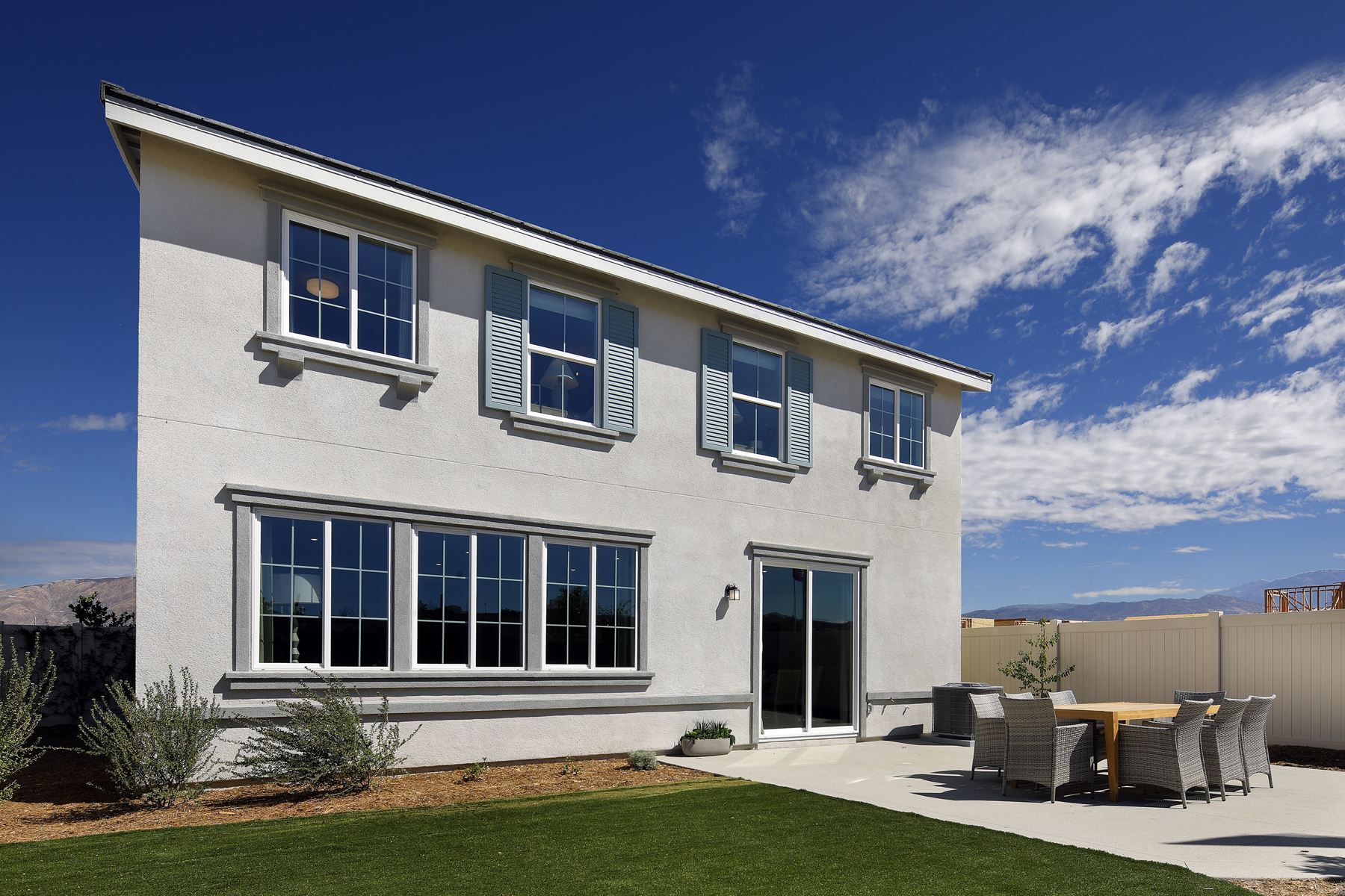 A white house with a lawn and chairs in front of it.