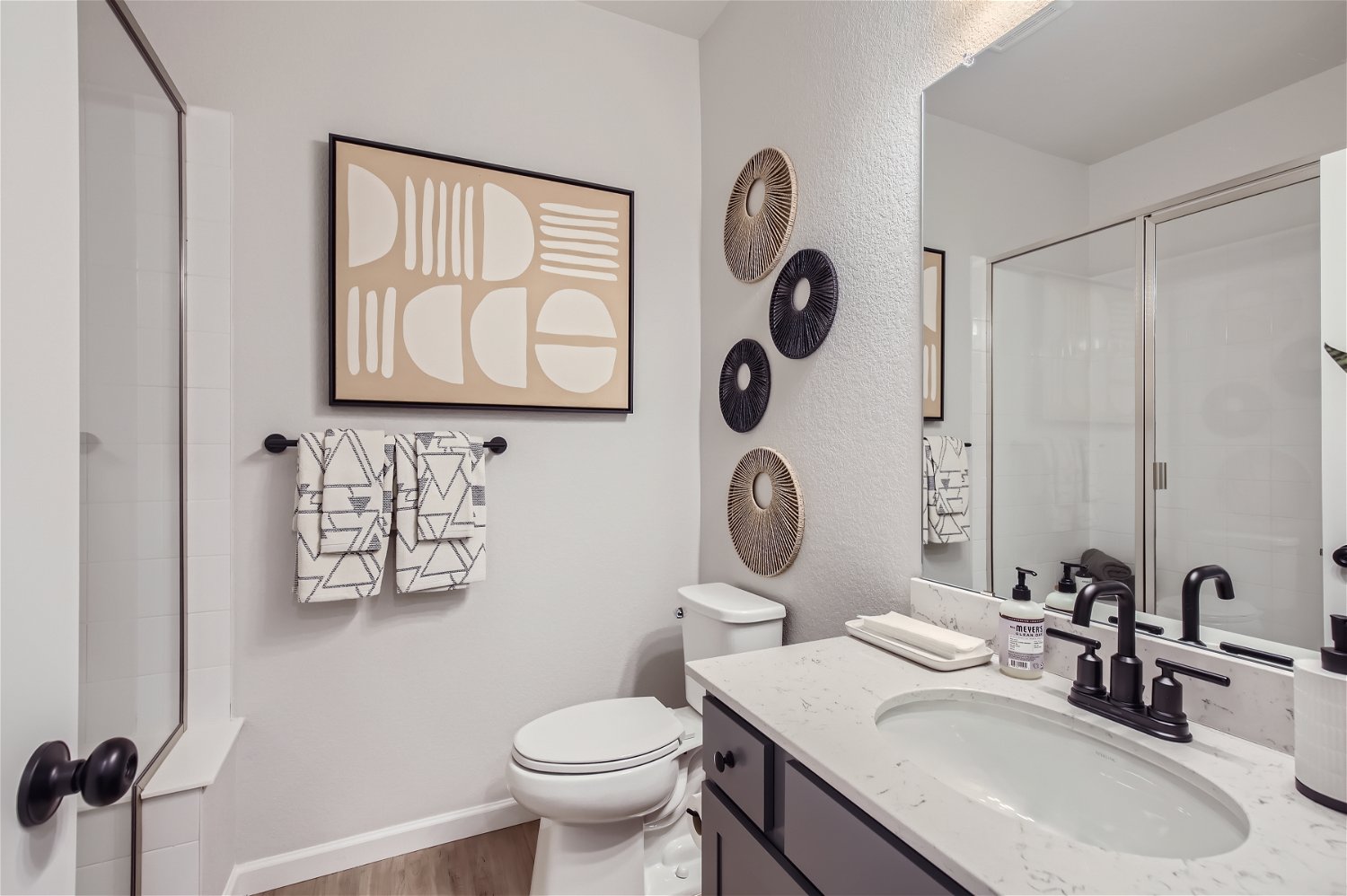 A bathroom with a sink toilet and a mirror.