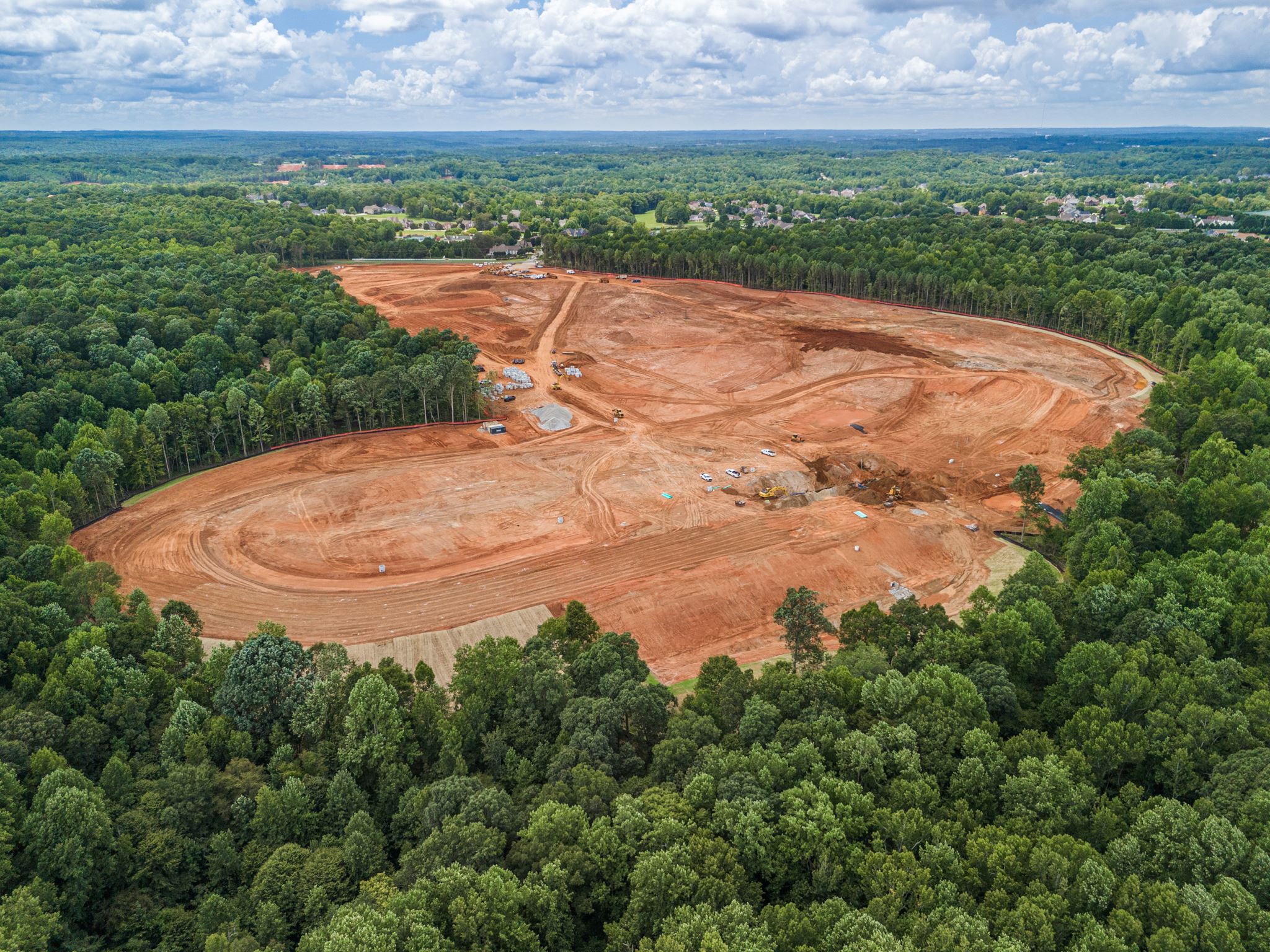 A large dirt field surrounded by trees.