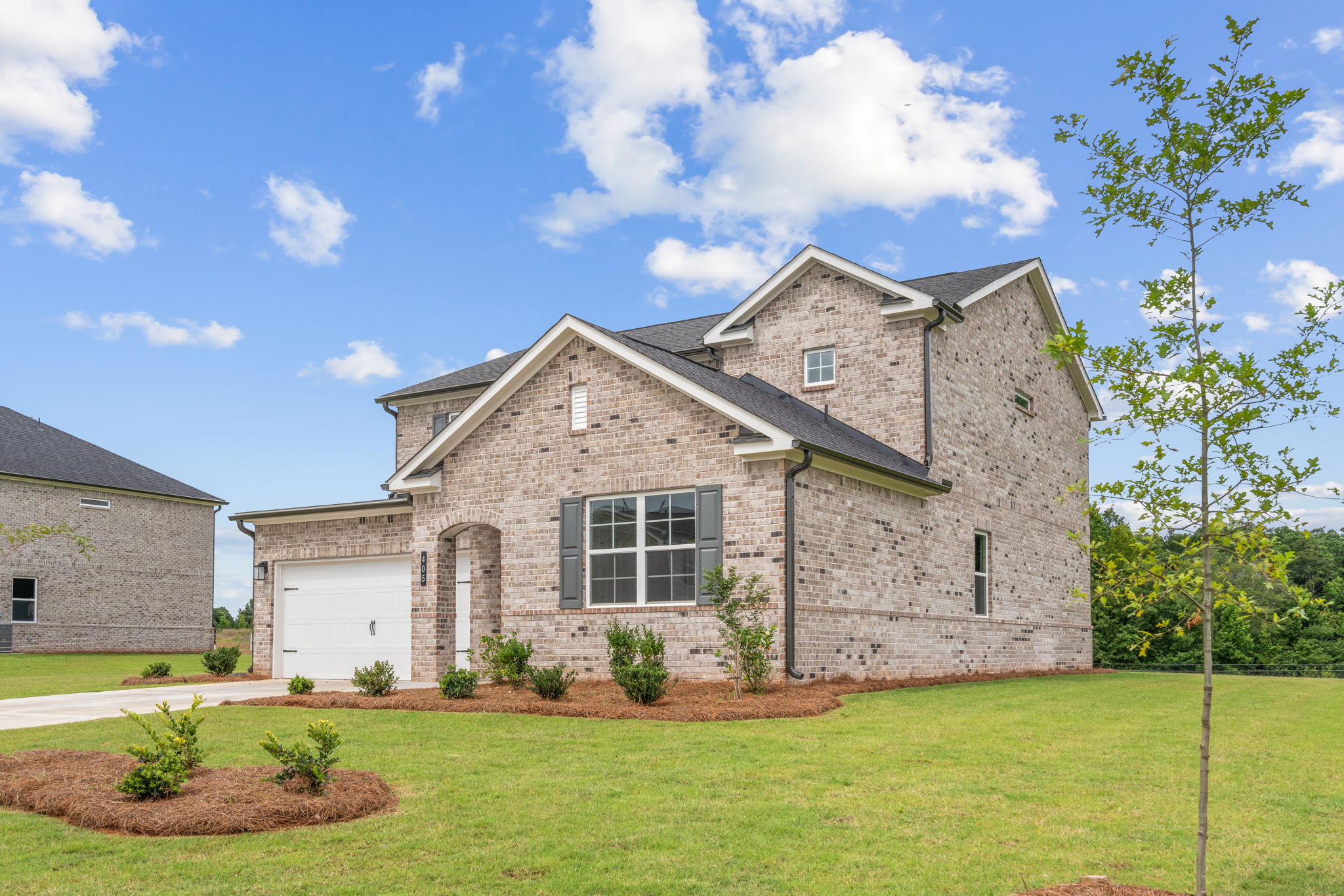 A house with a garage and a lawn in front of it.