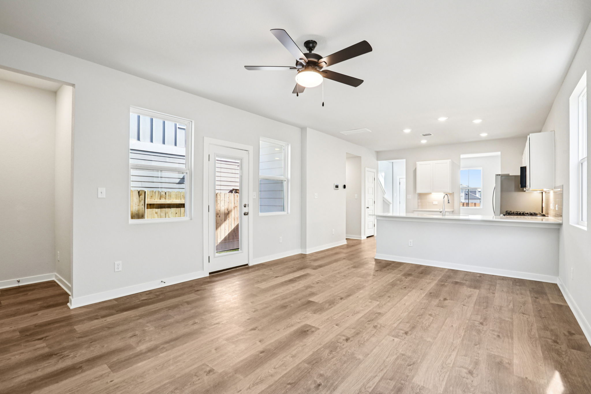 A room with white walls and a wood floor with a ceiling fan.