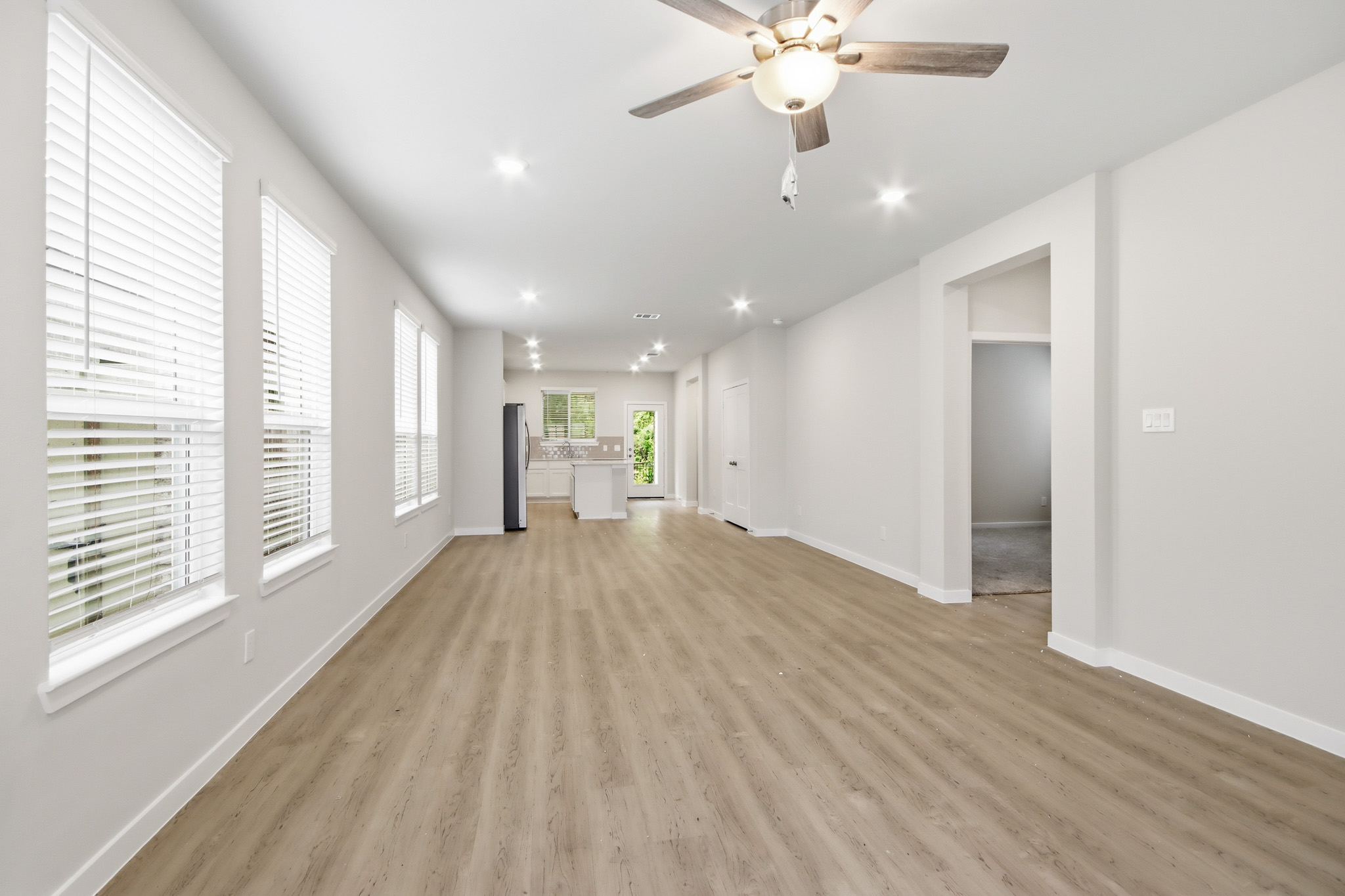A large empty room with a ceiling fan and a wood floor.