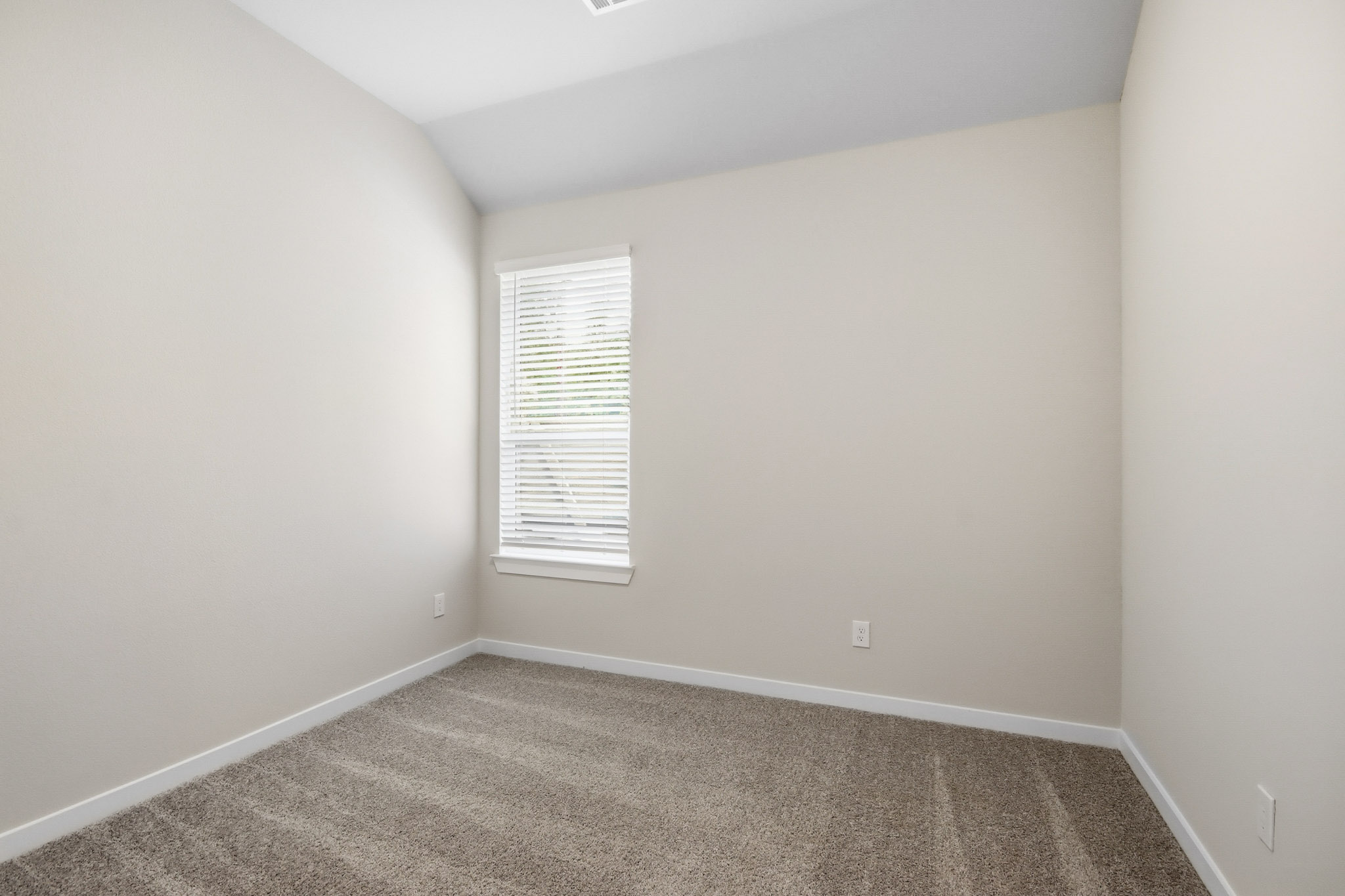A room with a carpet and a window.