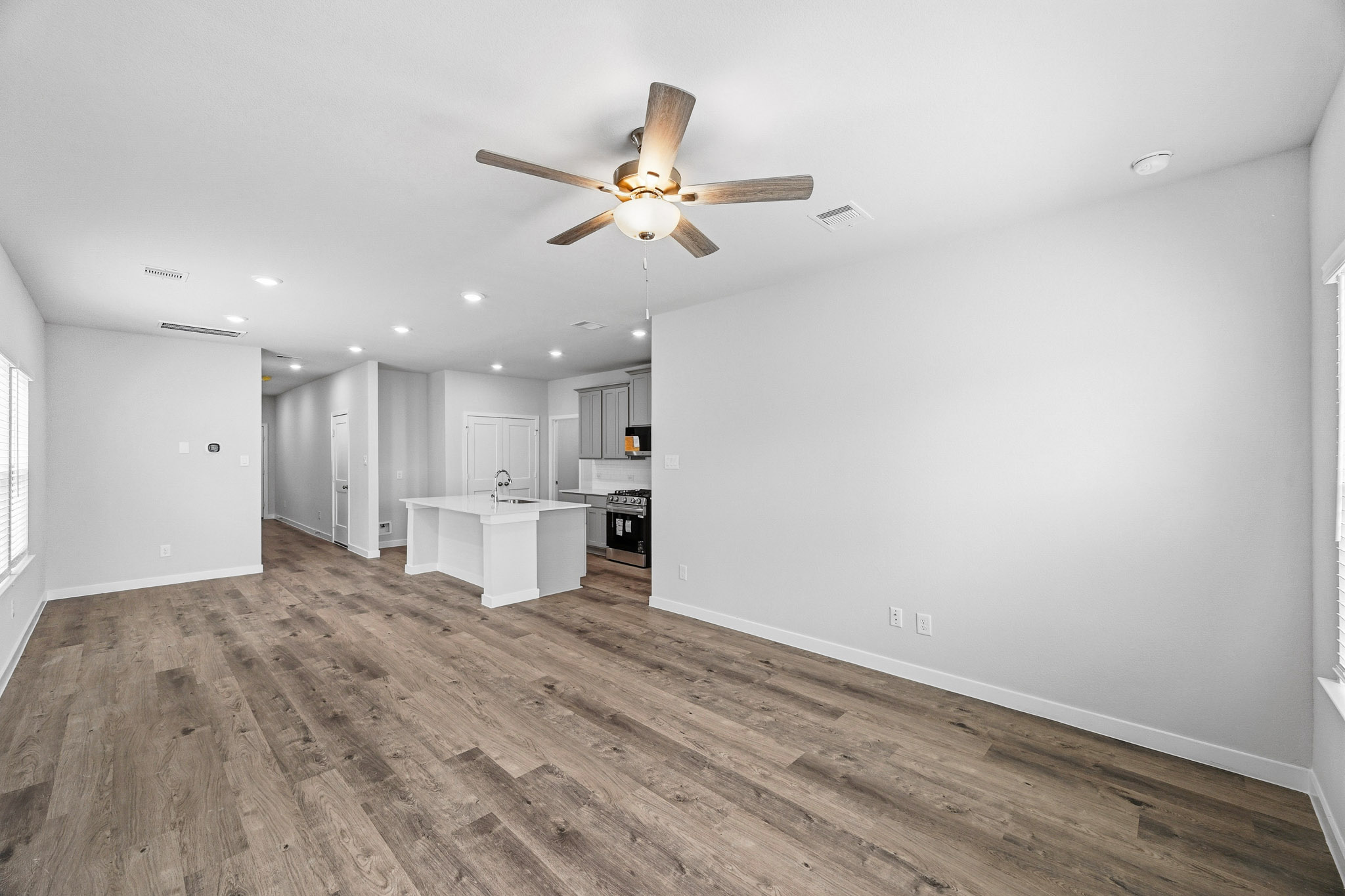 A large room with a ceiling fan and a wood floor.