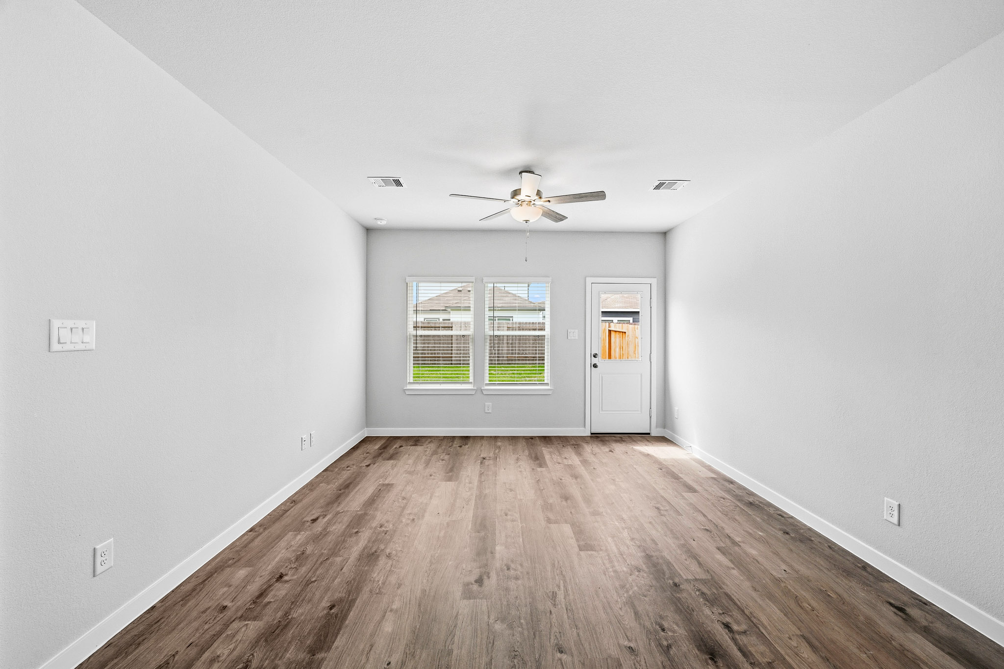 A room with a wood floor and a ceiling fan.