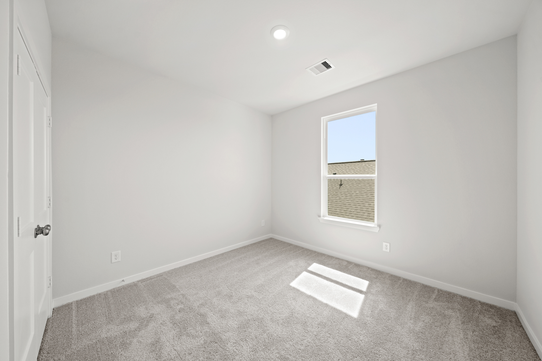 A room with a window and a rug on the floor.