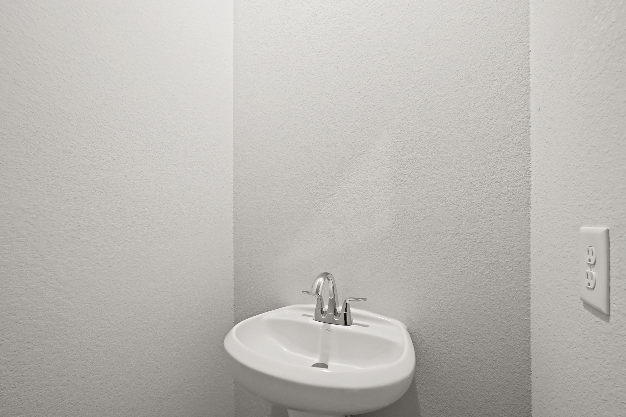 A white sink in a white room.