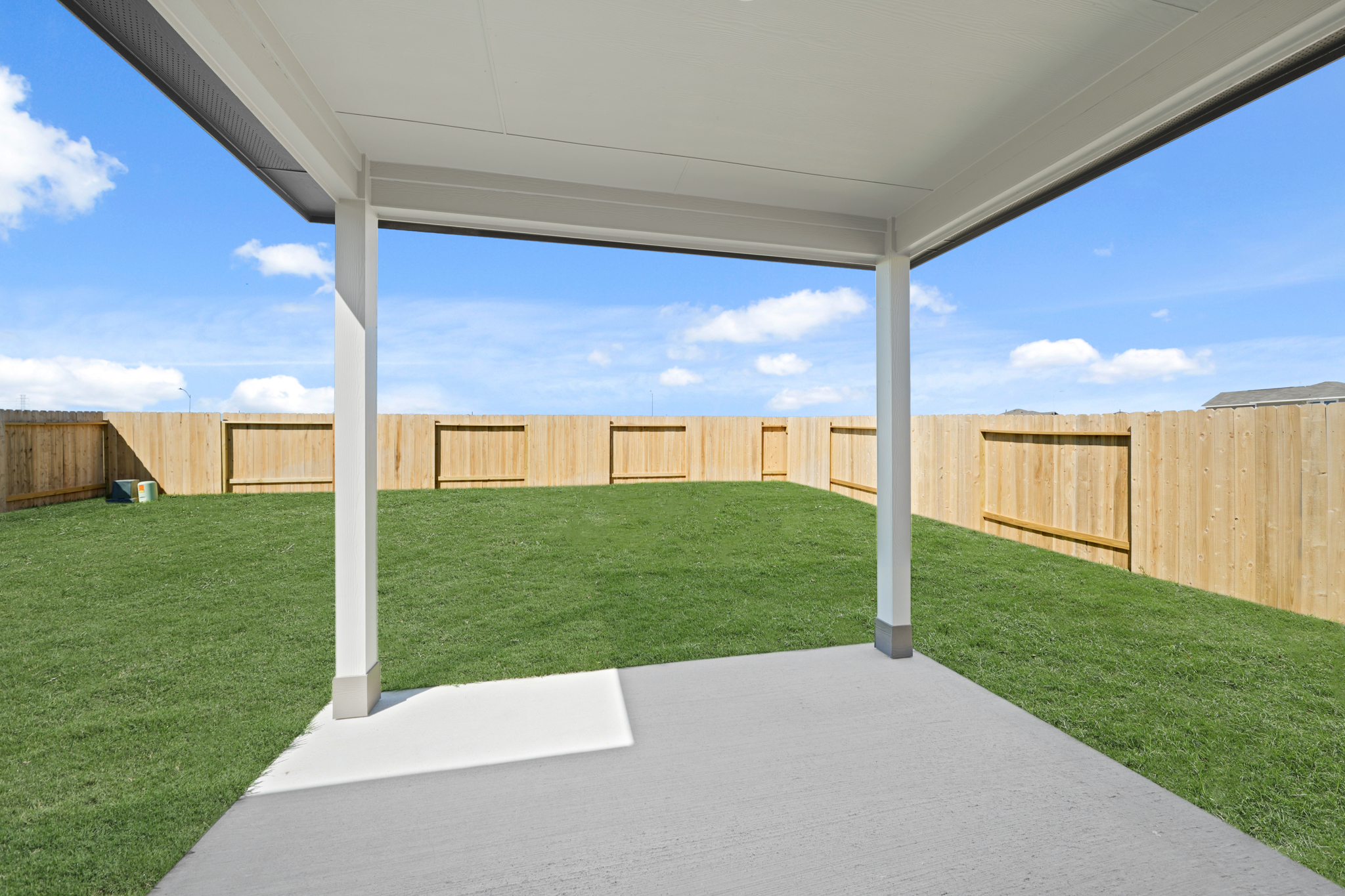 A fenced in area with a grass field and a building in the background.