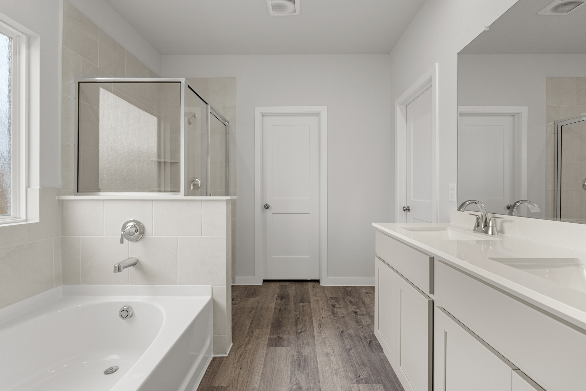 A bathroom with a tub sink and mirror.