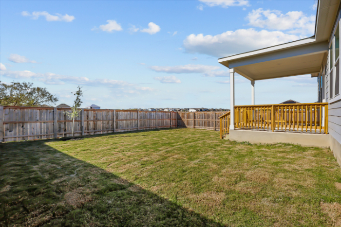 A fenced in yard with a building and trees in the background.