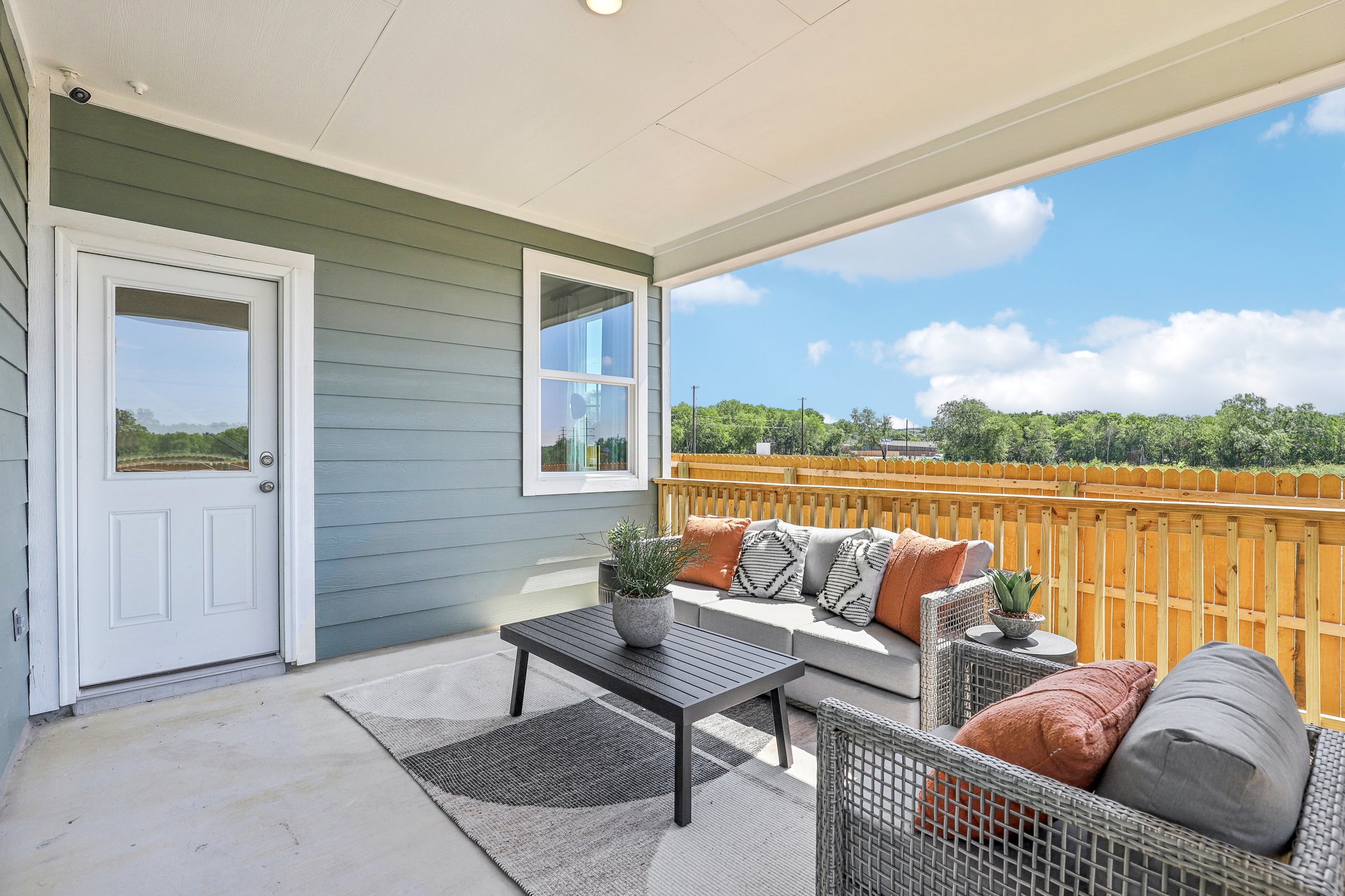 A patio with a couch and a table and a chair in front of it.